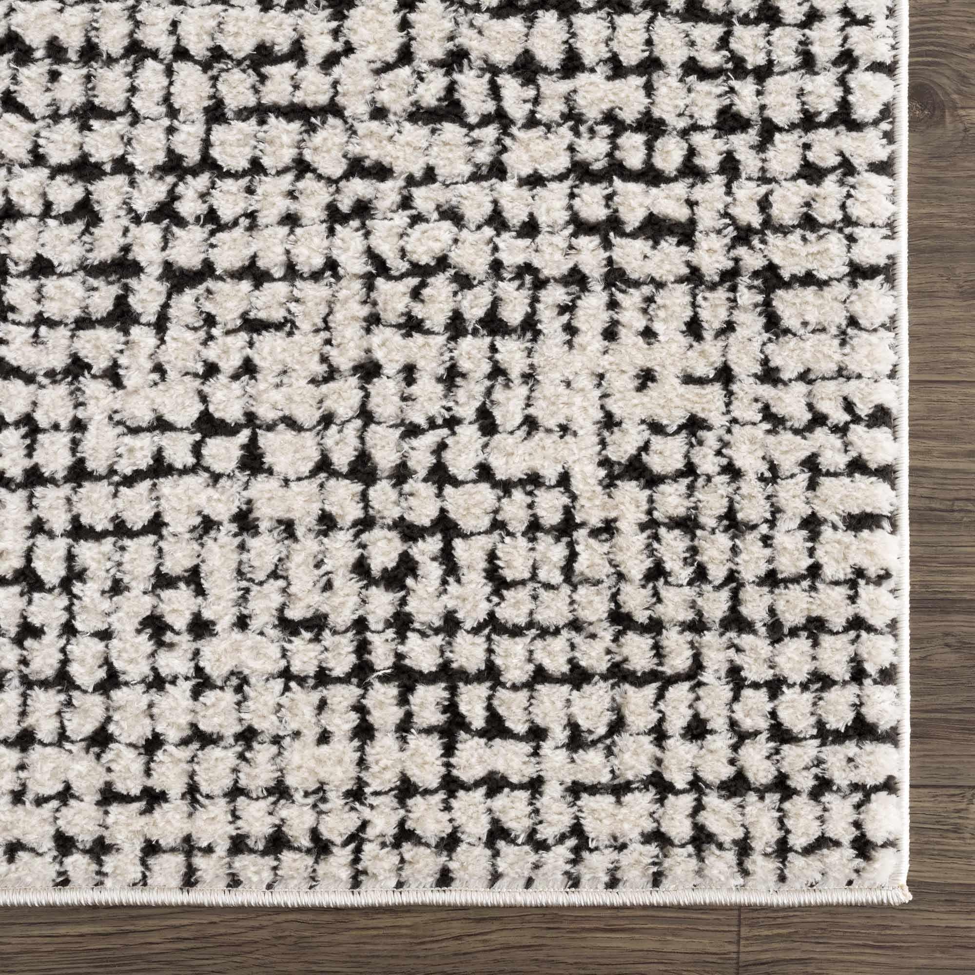 Black and white geometric patterned area rug with plush texture on wood floor, farmhouse style home decor