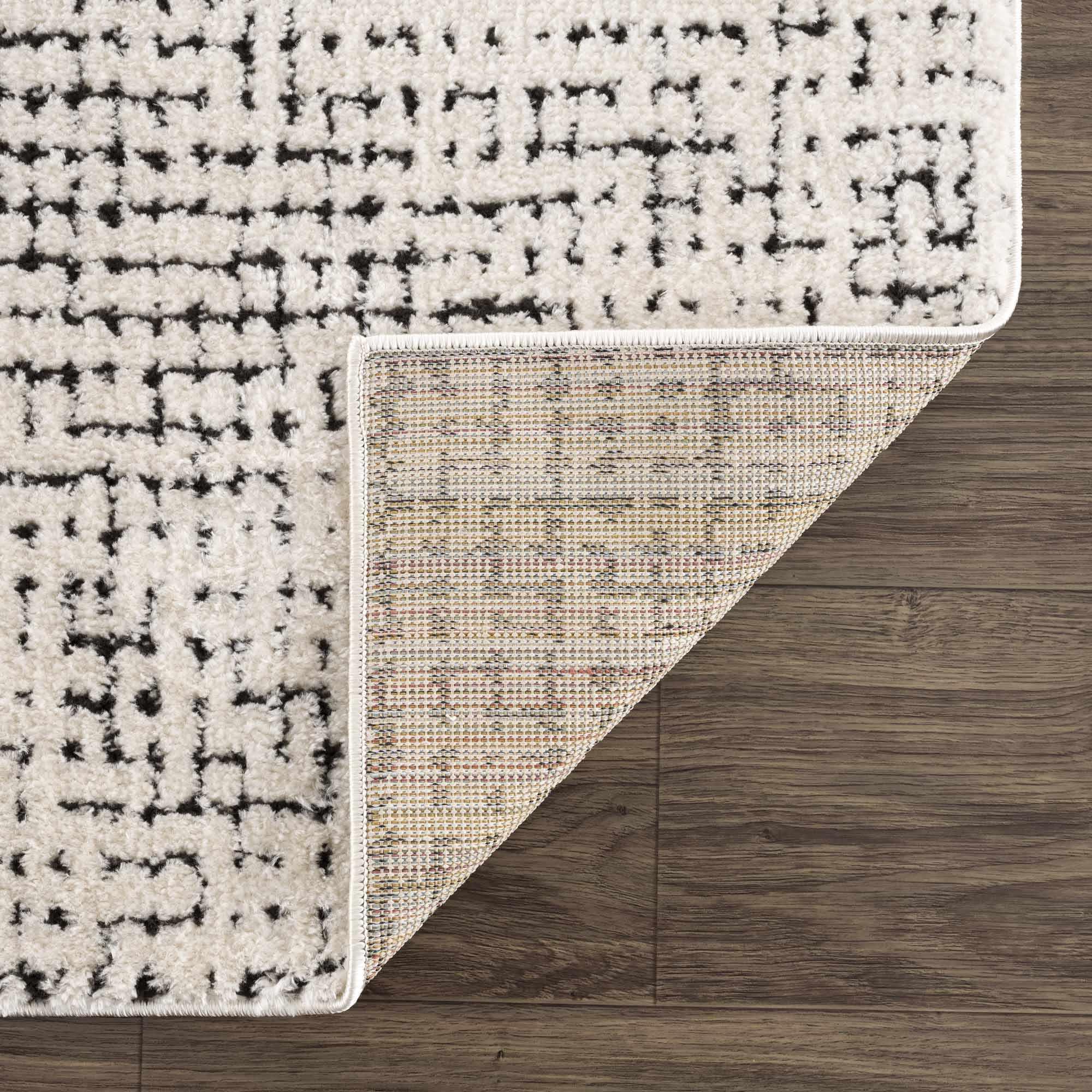Cream and black patterned area rug with textured weave, shown on wood floor, farmhouse style home decor