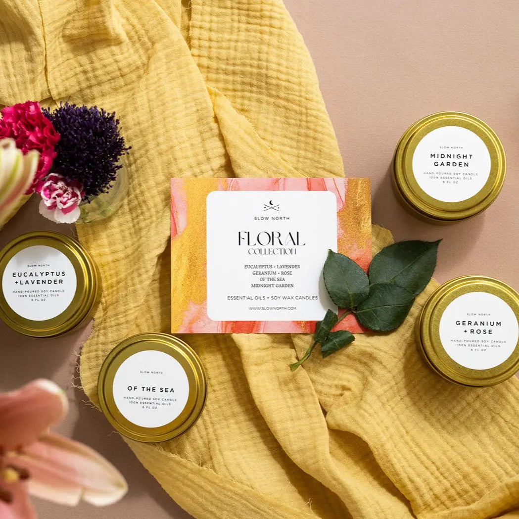 Floral collection soy candles with essential oils, nestled on yellow fabric with fresh flowers, perfect for cozy home decor.
