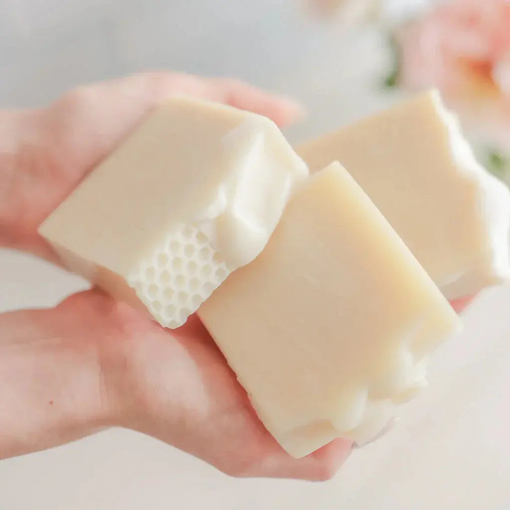 Hand holding creamy honeycomb-textured soap bars, cozy farmhouse bath essentials