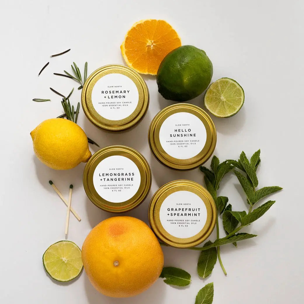Hand-poured soy candles with citrus and herb scents, surrounded by fresh lemons, limes, oranges, and mint leaves.
