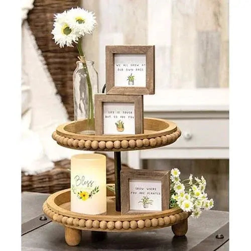 Two-tier wooden display stand with decorative items including framed pictures and a candle.