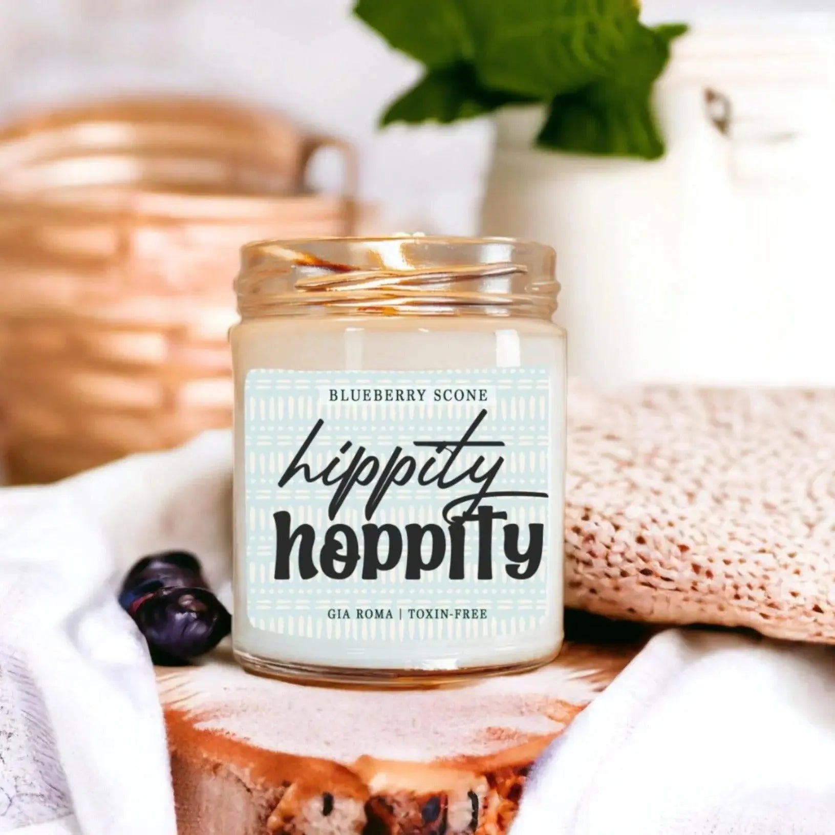 Candle labeled 'hippity hippity' with a blueberry scone design on a decorative surface.