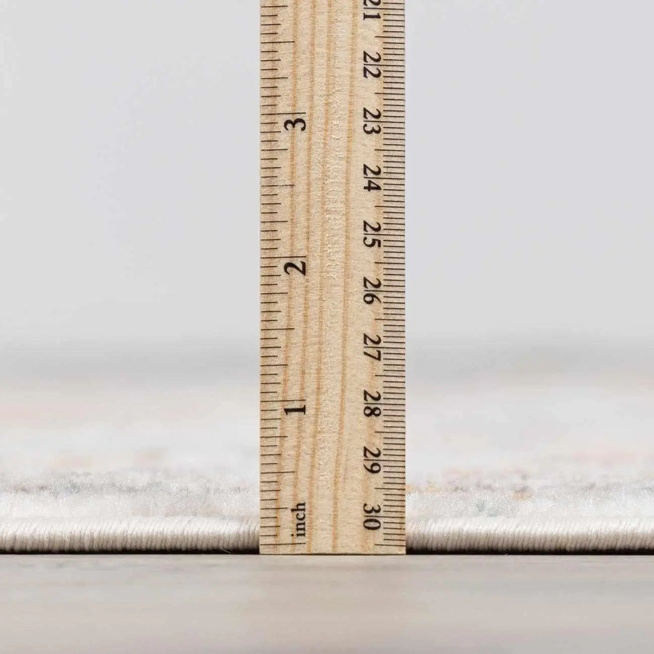 Wood ruler measuring cozy farmhouse rug thickness, showing 3-inch pile height for soft home decor