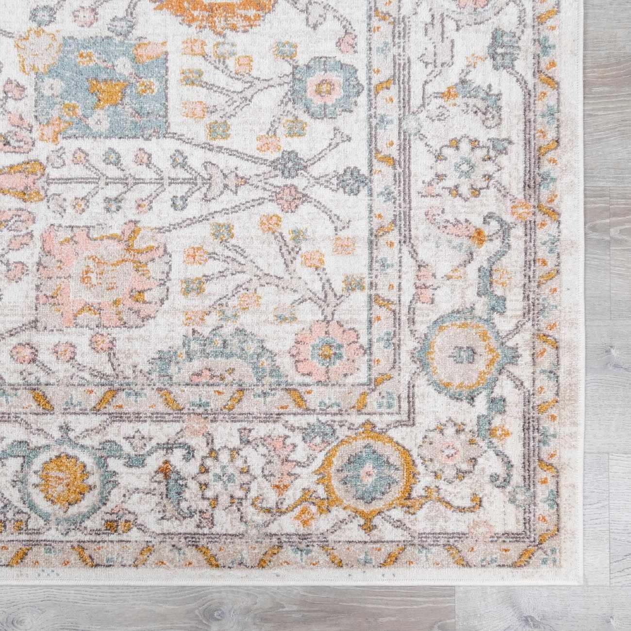 Cozy farmhouse area rug with floral medallion pattern in soft pastel tones on light wood floor