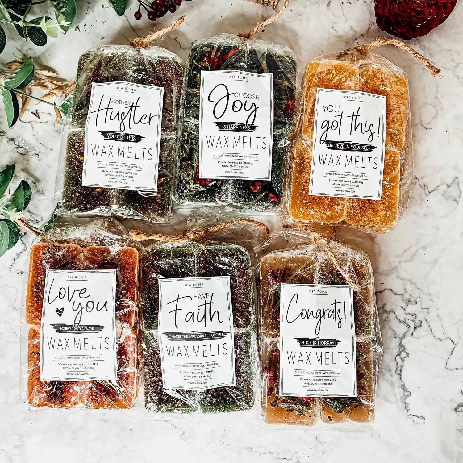 Packaged wax melts with motivational labels on a marble surface