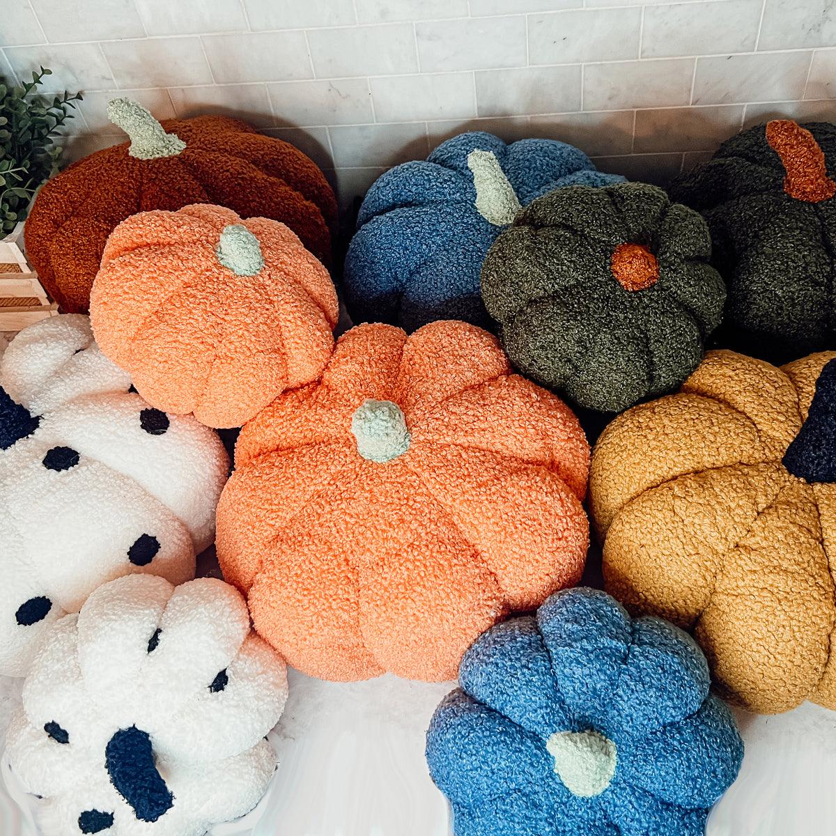 Colorful pumpkin-shaped cushions arranged on a tiled floor.