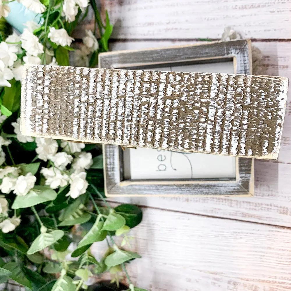 Decorative silver box with textured surface on a wooden background with flowers
