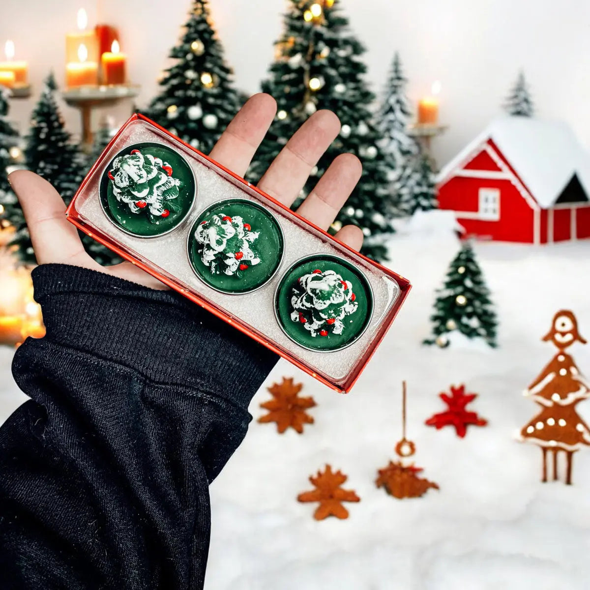 Hand holding a set of green Christmas-themed cookies with festive background