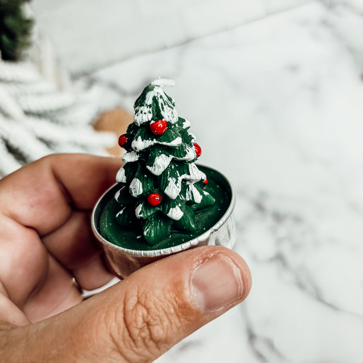 Small Christmas tree figurine held in a hand with a blurred background