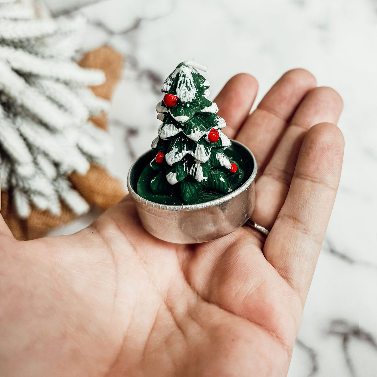 Small Christmas tree decoration held in a hand with a blurred snowy background