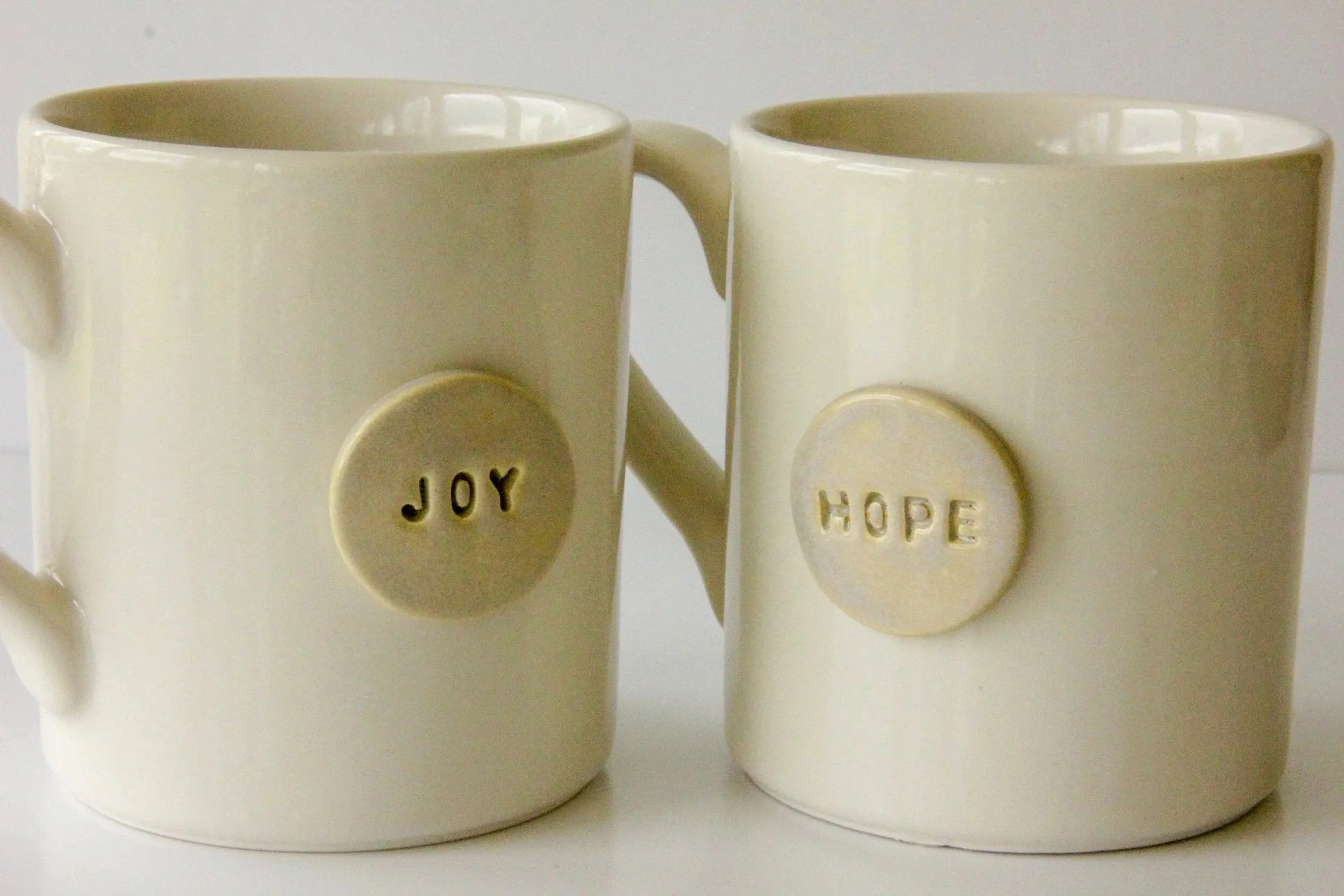 Cream ceramic mugs with 'Joy' and 'Hope' embossed, cozy farmhouse style home decor