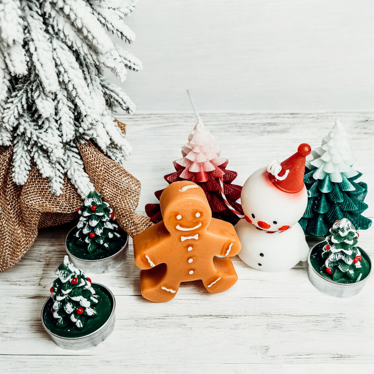 Decorative Christmas items including a gingerbread man, snowman, and miniature trees on a wooden surface.