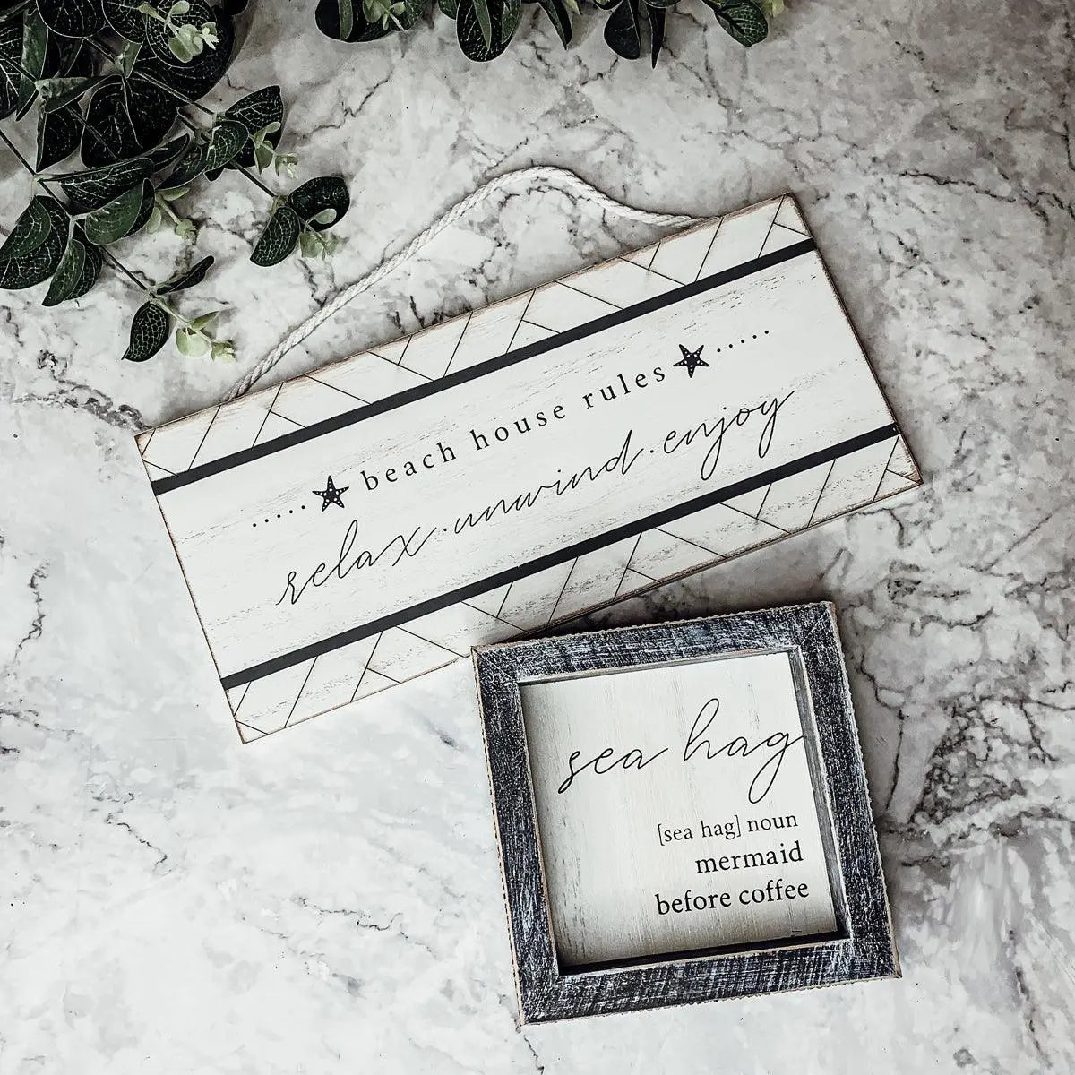 Beach house rules sign and sea hag mermaid decor on marble with greenery