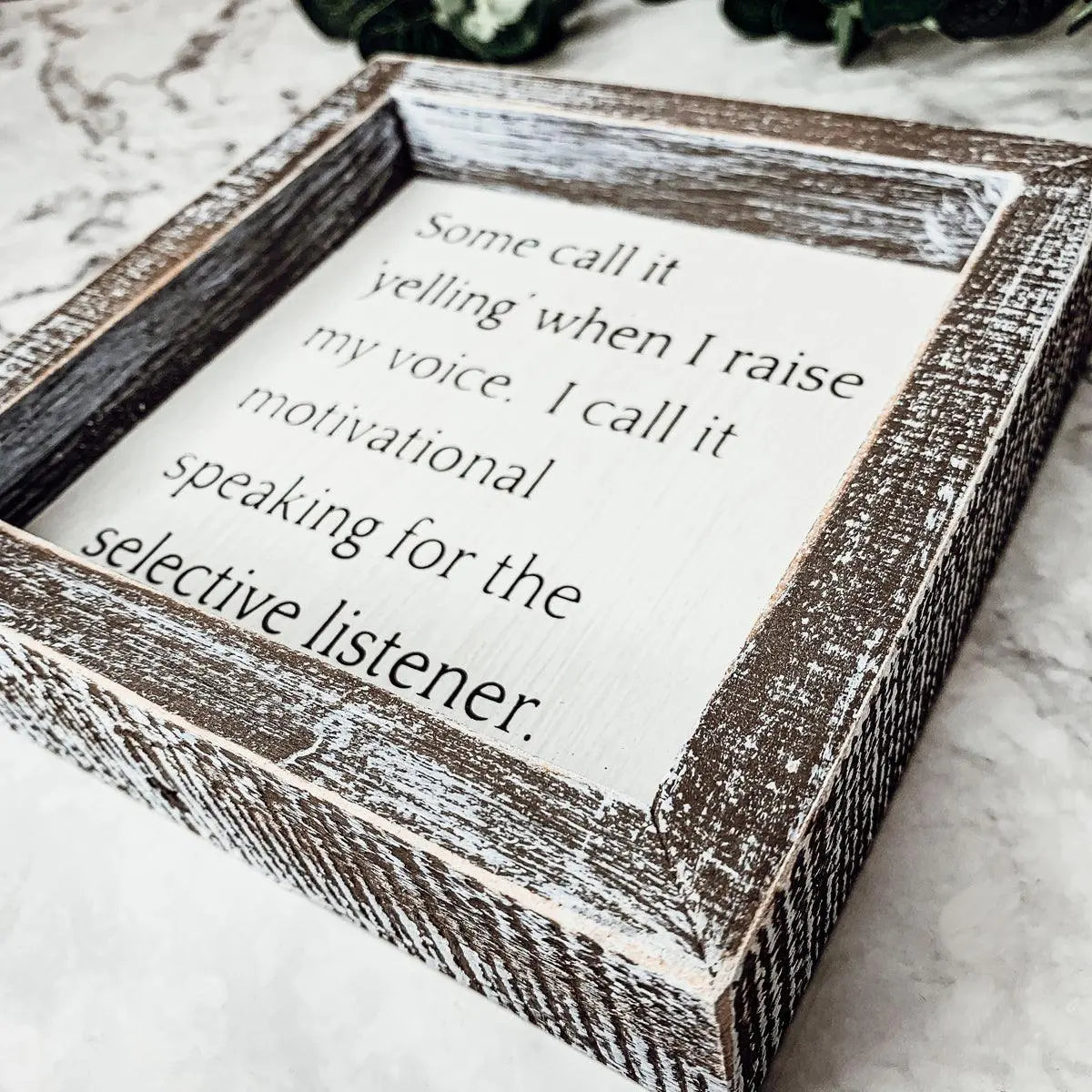 Wooden framed sign with motivational quote on a marble surface