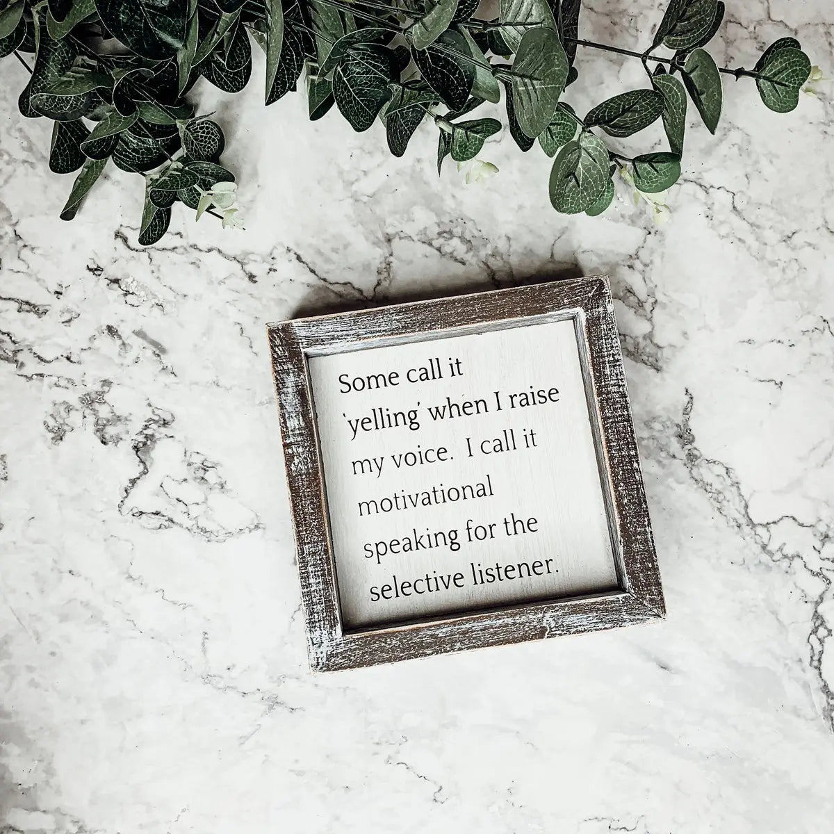 Framed quote on a marble surface with greenery