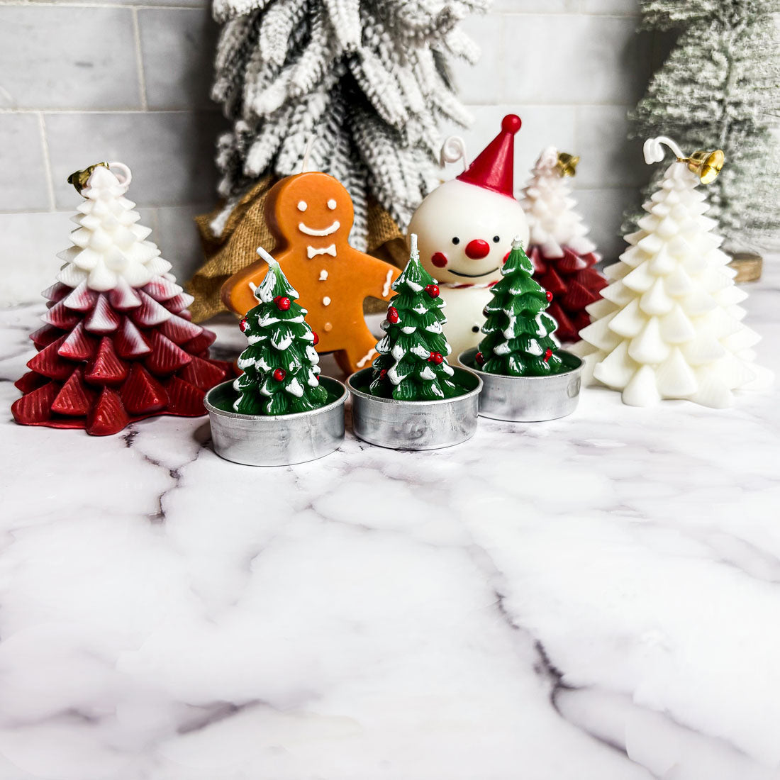 Set of Christmas-themed candles on a marble surface with decorative background