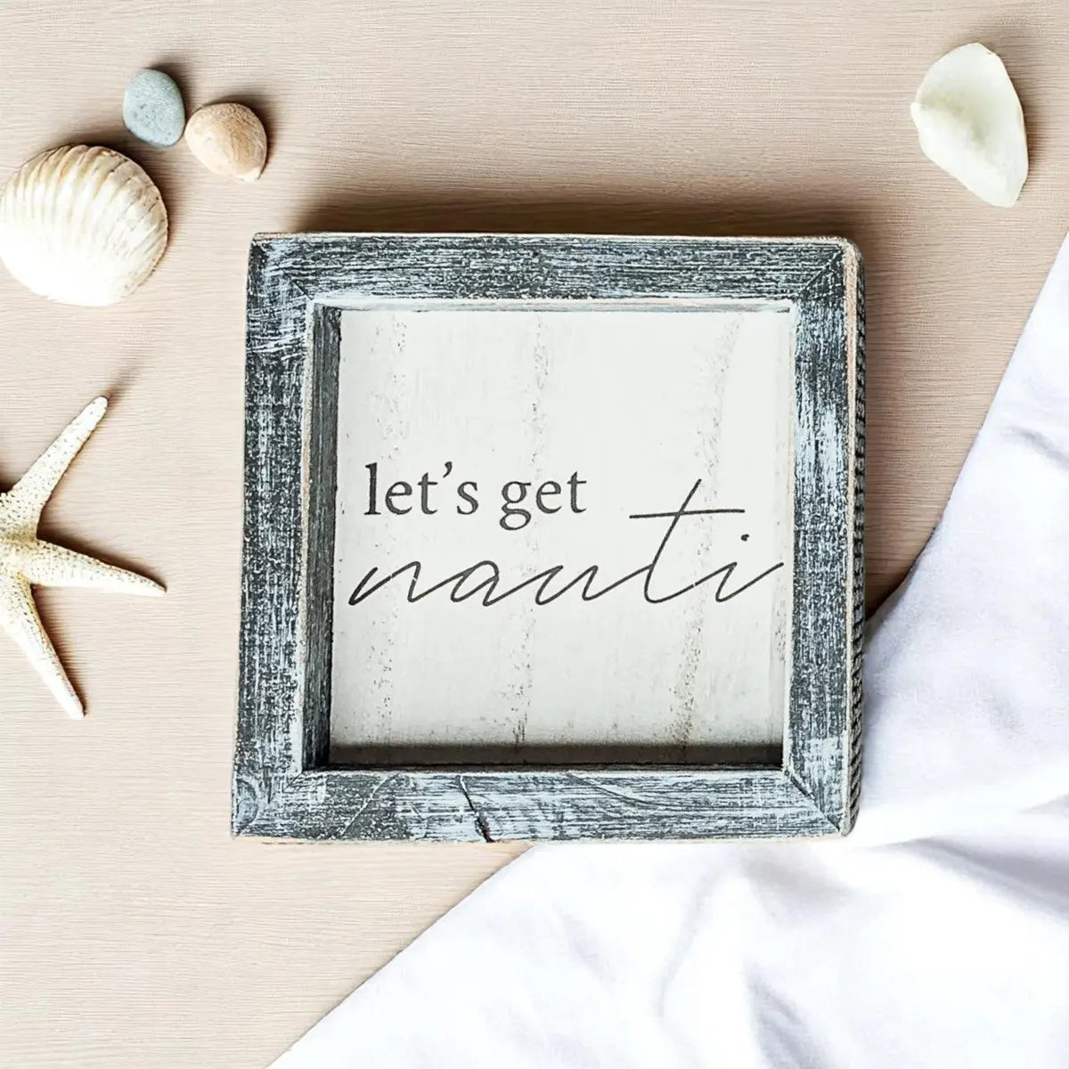 Framed sign with 'let's get nauti' text on a beach-themed background with shells and starfish.