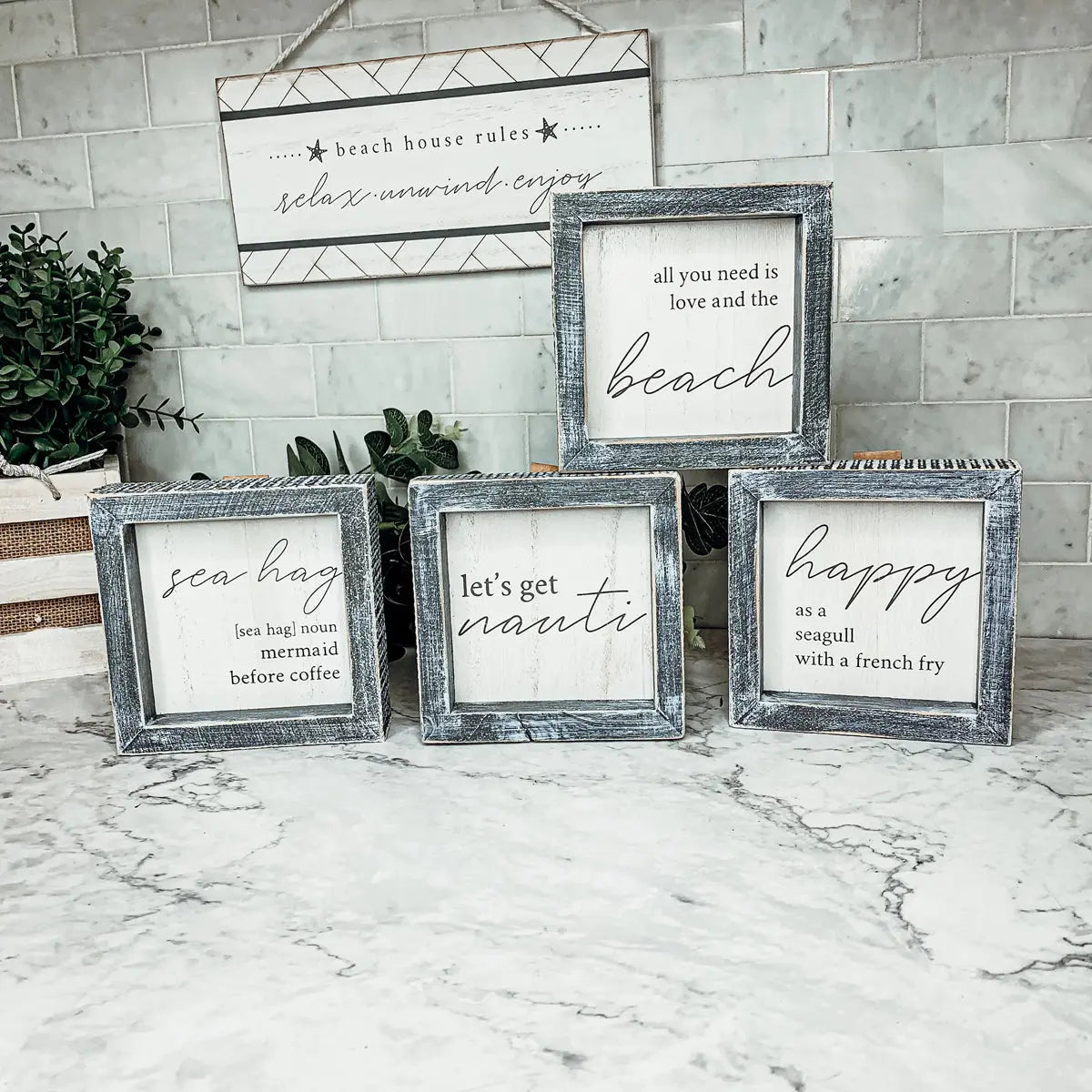 Set of framed signs with beach-themed quotes on a marble surface.