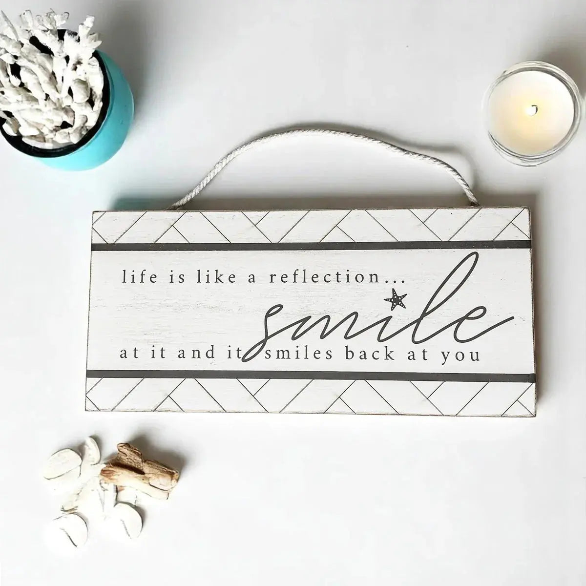 Decorative sign with motivational quote on a white surface with decorative items.