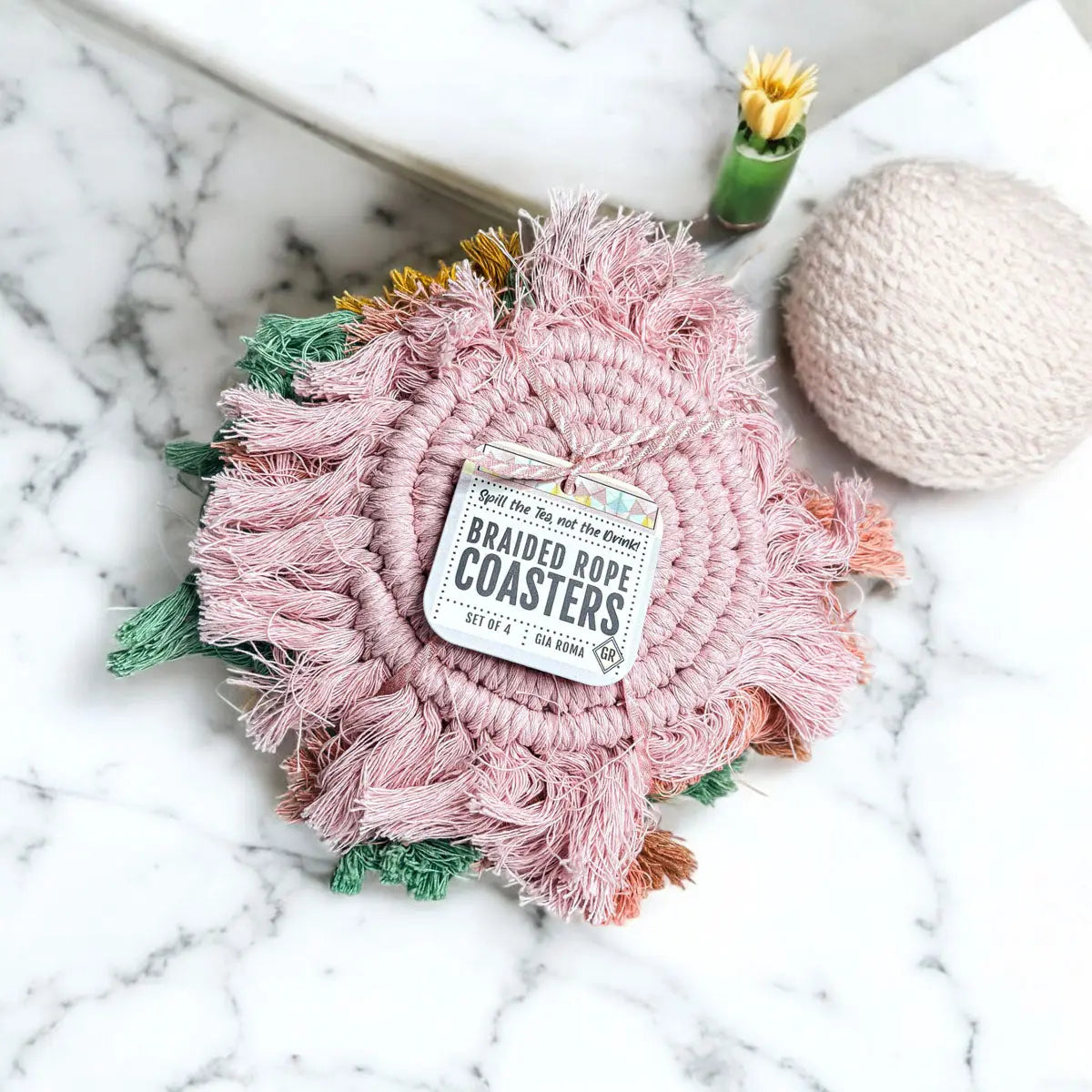 Pink braided rope coaster with a label on a marble surface