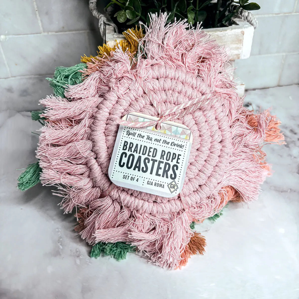 Pink braided rope coasters with a tag on a marble surface