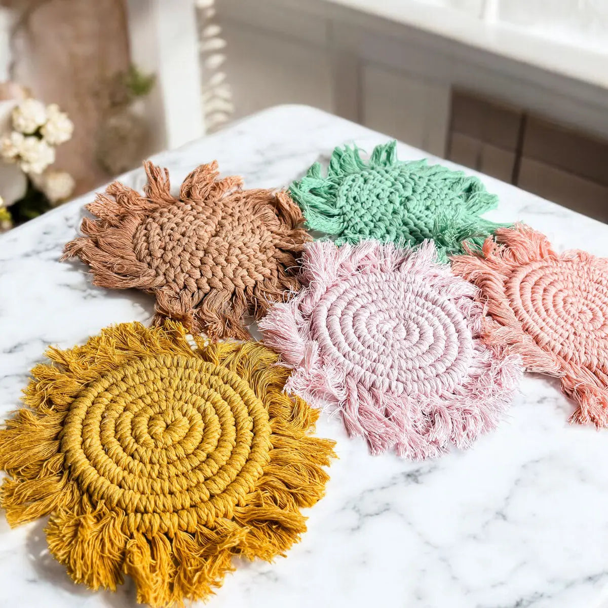 Set of colorful woven coasters on a marble surface