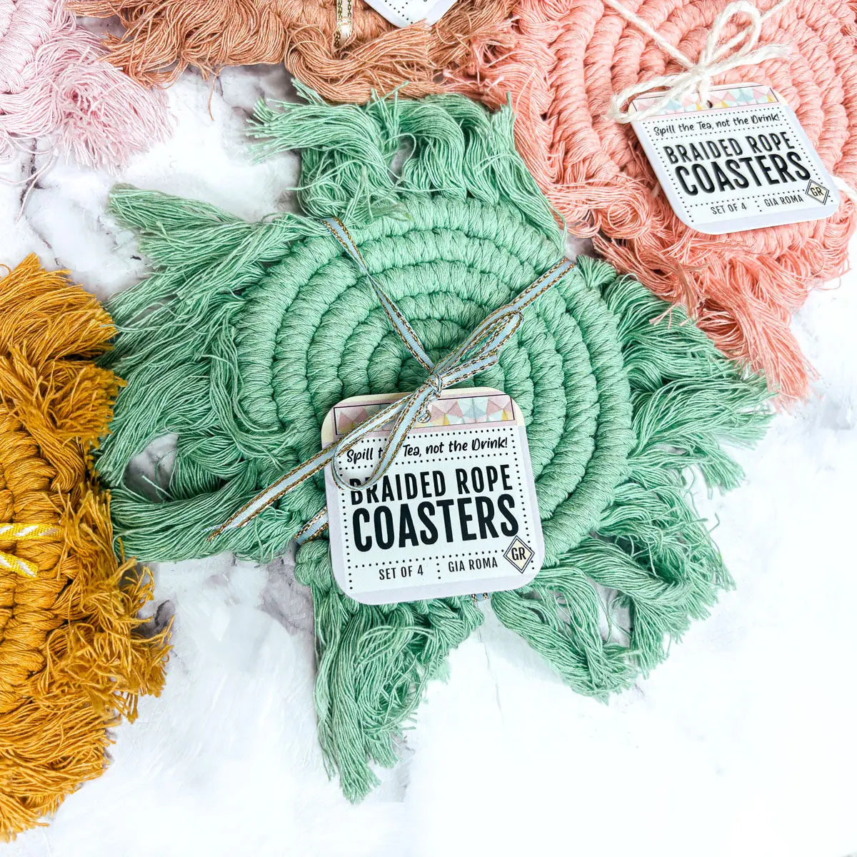 Set of braided rope coasters with tags on a marble surface