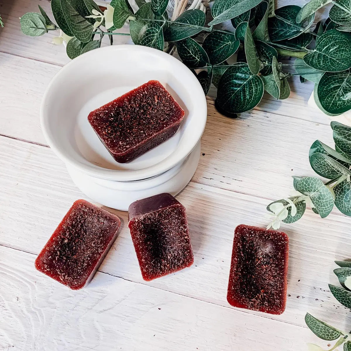 Rectangular dark red jelly-like blocks on a white surface with green leaves in the background