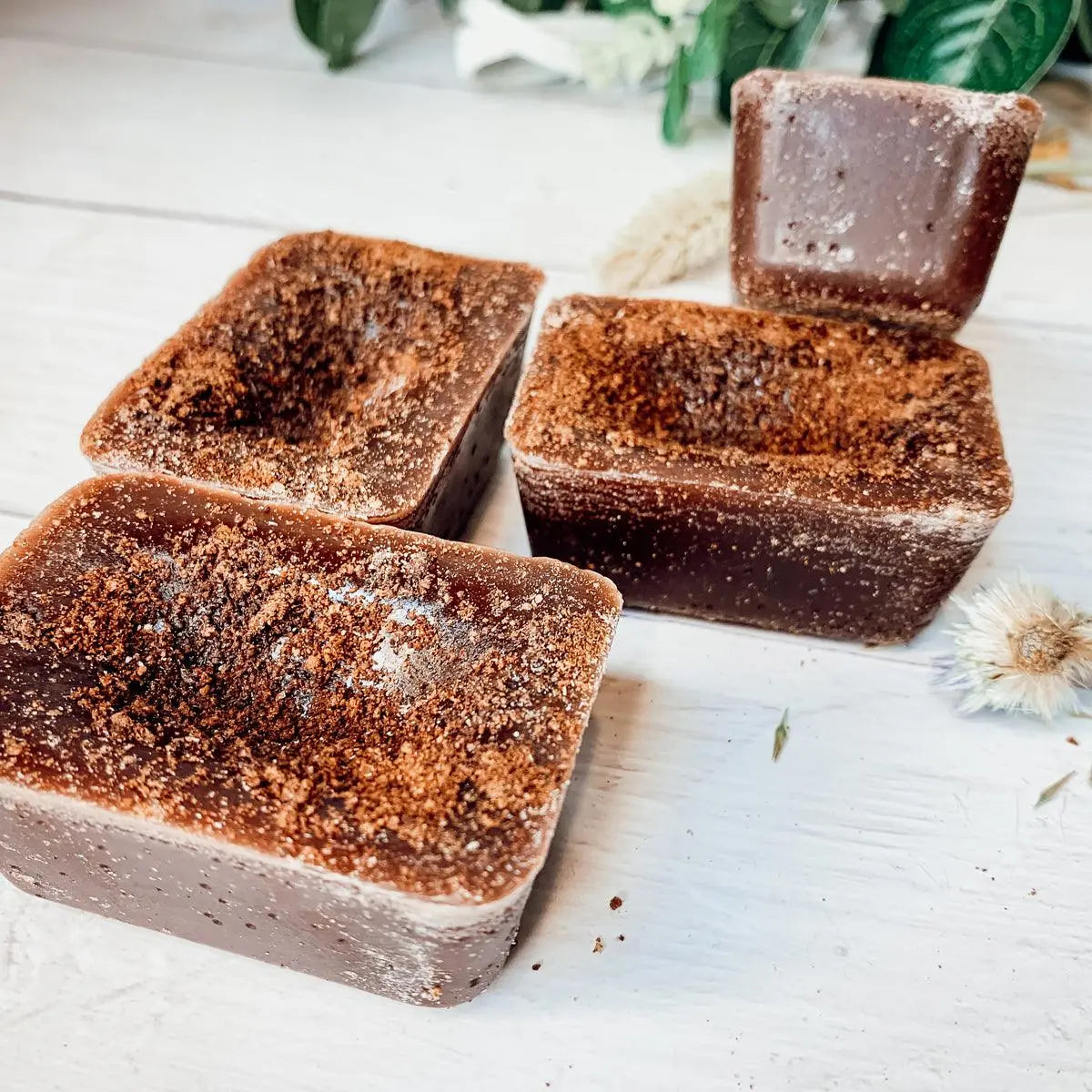 Chocolate soap bars with a textured surface on a light wooden background