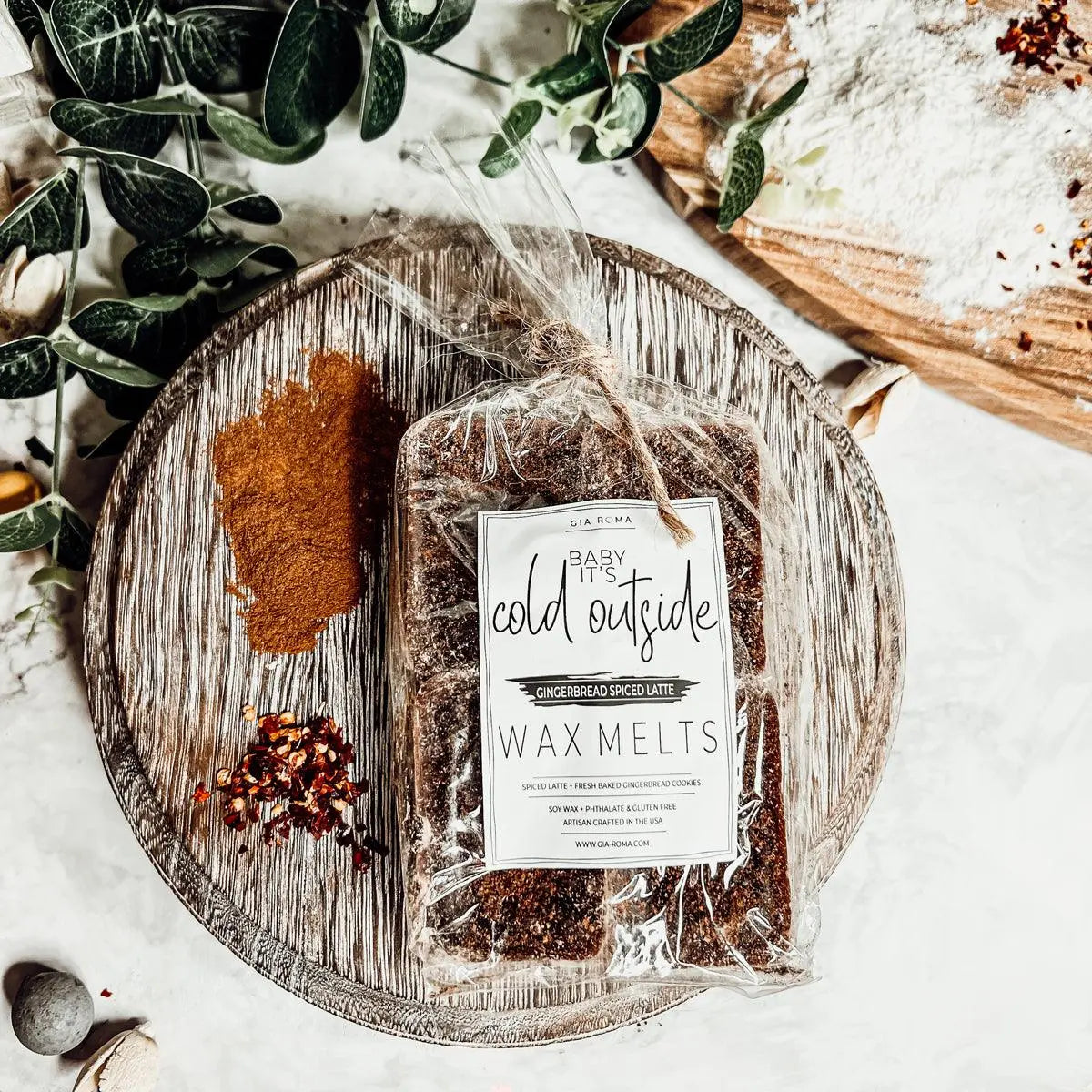 Packaged wax melts with a label on a wooden tray with decorative elements.