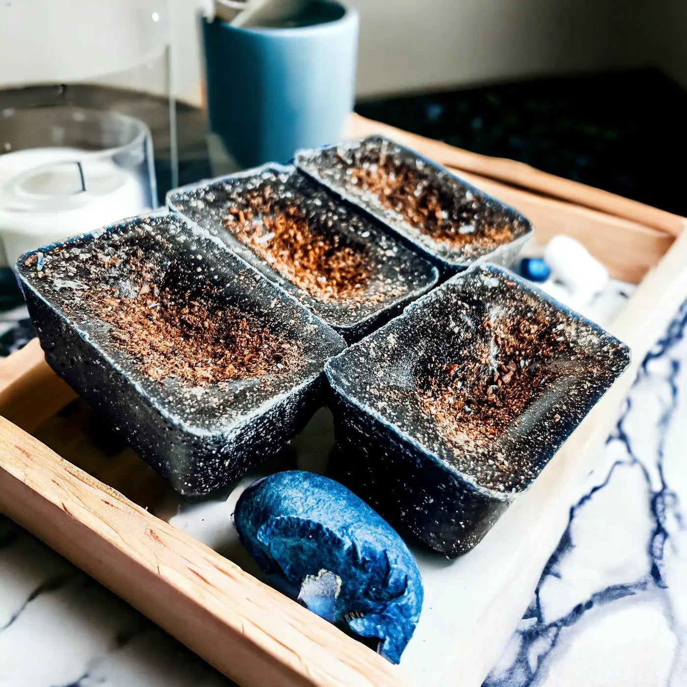 Four black containers with brown substance on a marble surface