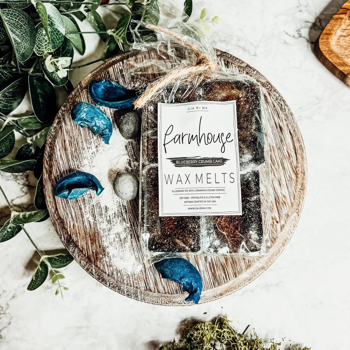 Packaged wax melts labeled 'Farmhouse' on a wooden tray with decorative elements.