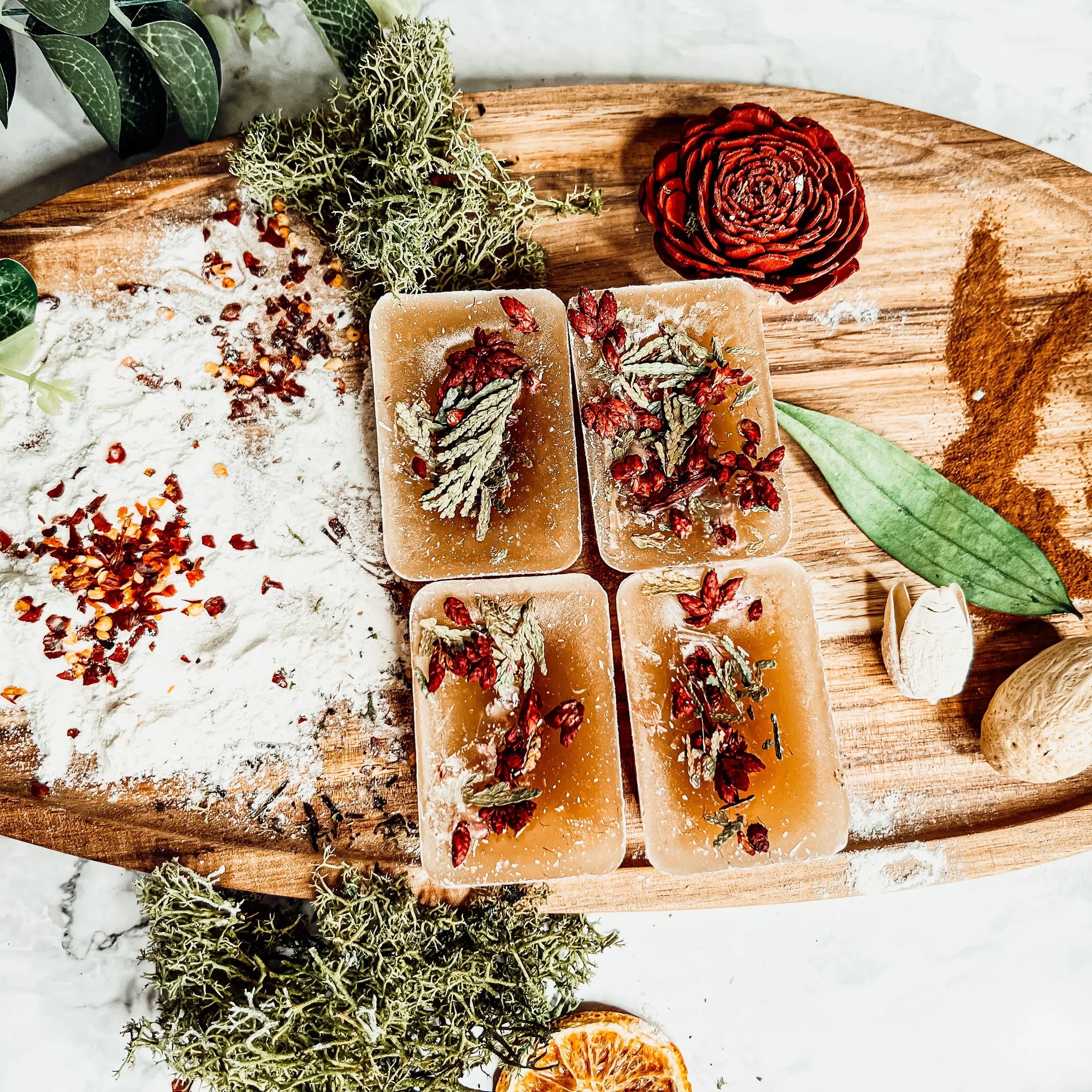Herbal bath salts in square containers on a wooden board with herbs and spices.