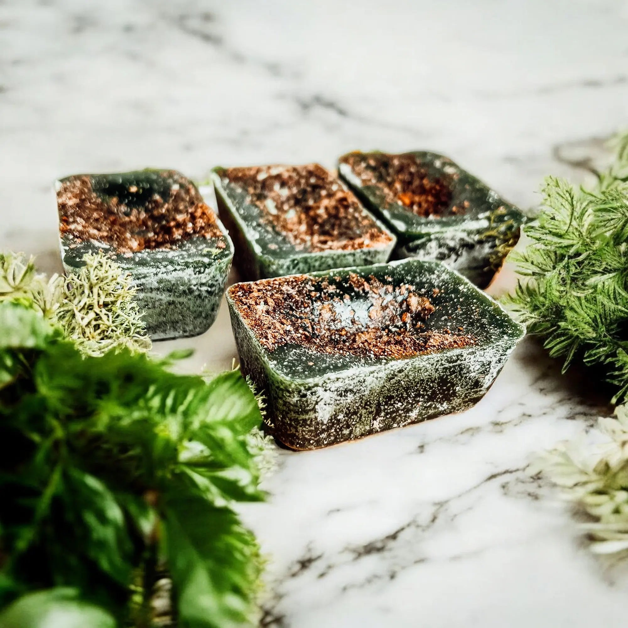 Green soap bars with brownish top on a marble surface with greenery