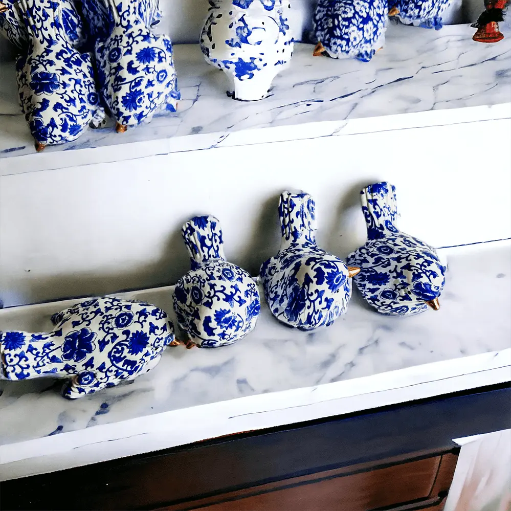 Blue and white ceramic ducks on a marble surface with a mirror reflection.