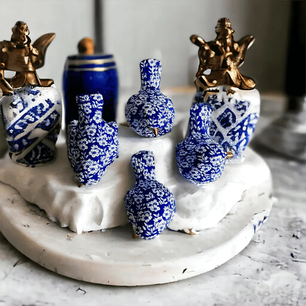 Decorative set of blue and white ceramic vases with gold accents on a marble surface.