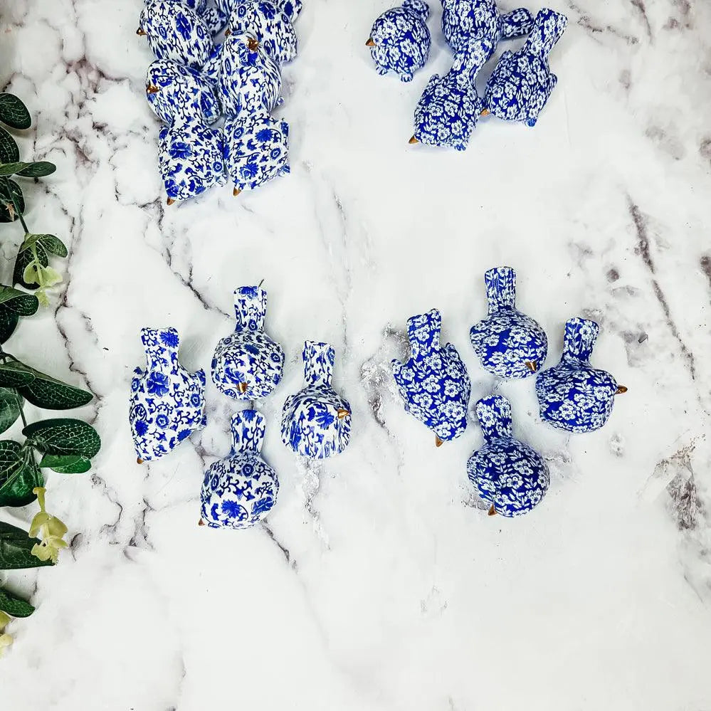 Blue and white ceramic ducks on a snowy surface with greenery.