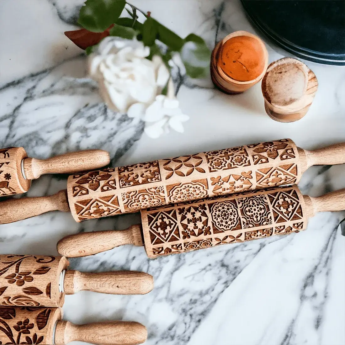 Set of wooden embossing rolling pins with intricate patterns on a marble surface.