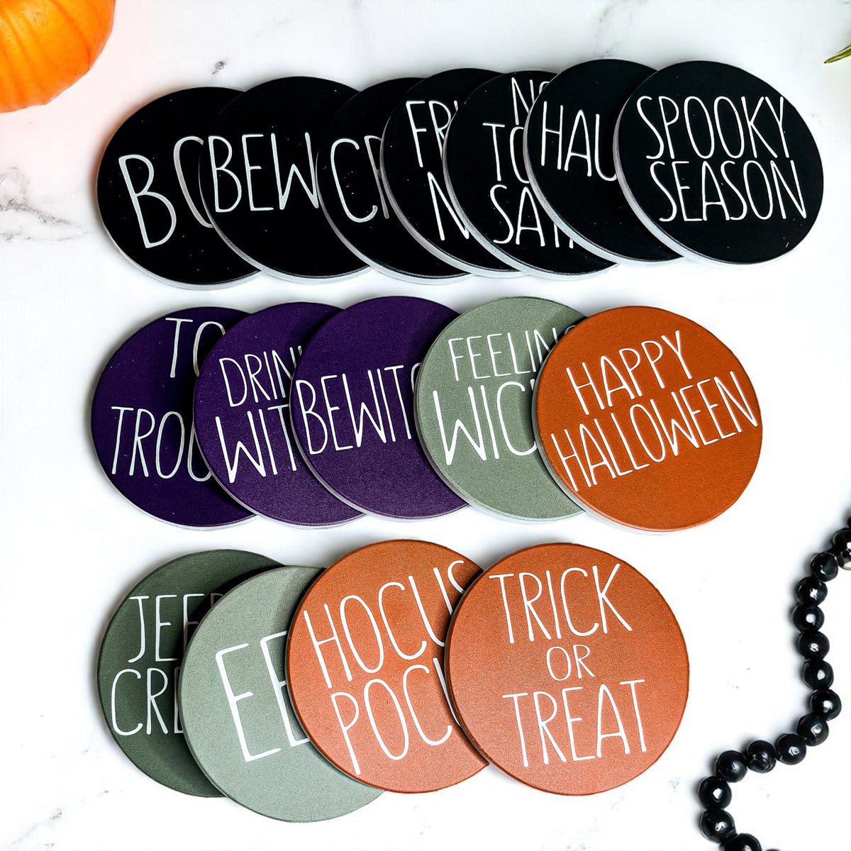 Set of Halloween-themed coasters with various sayings on a white surface.