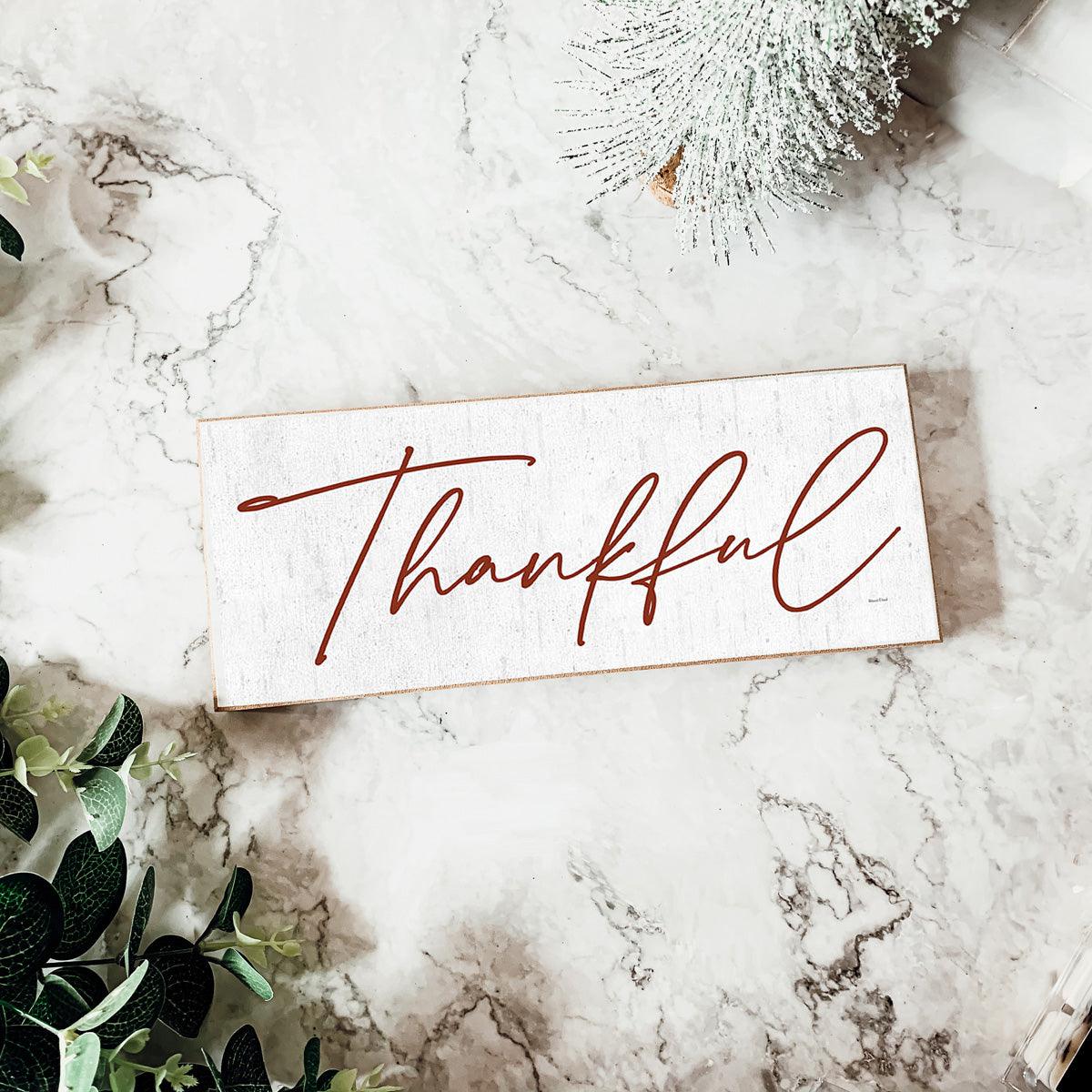 Card with 'Thankful' text on a marble surface with decorative elements