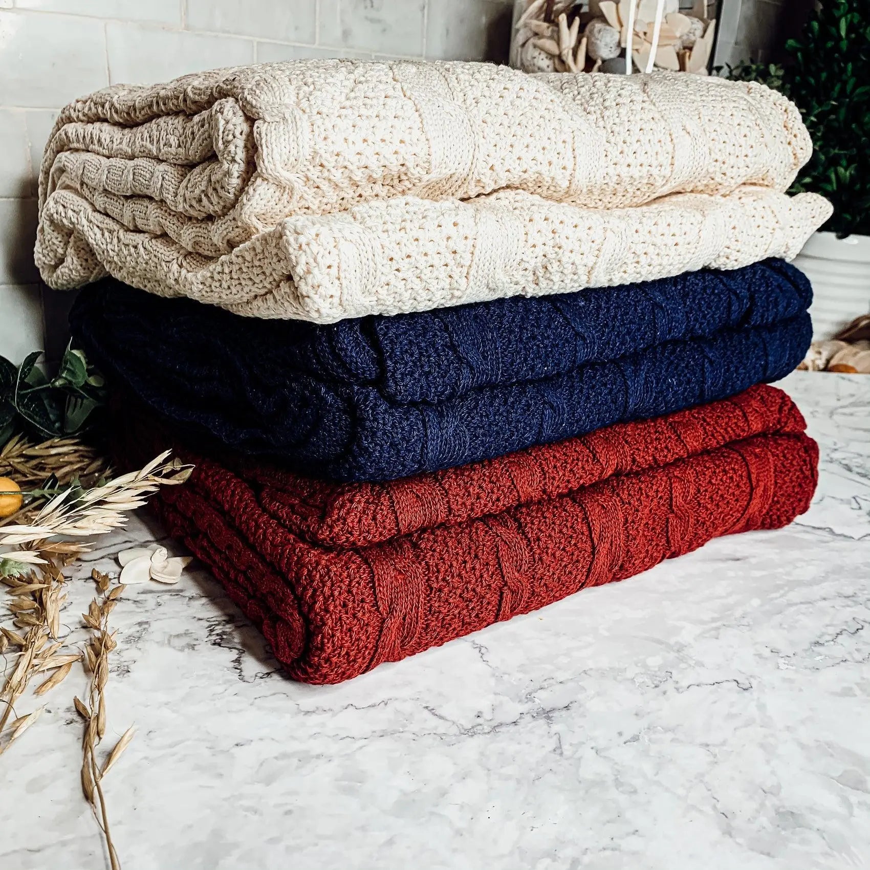 Cozy cable knit blankets in cream, navy, and red for farmhouse decor
