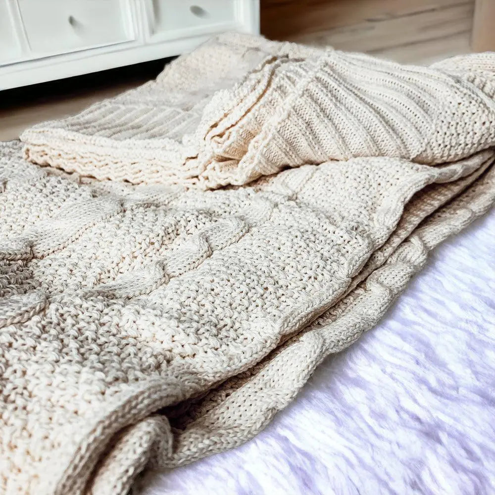 Cozy cream knit blanket with cable pattern, perfect for farmhouse or cottage style decor