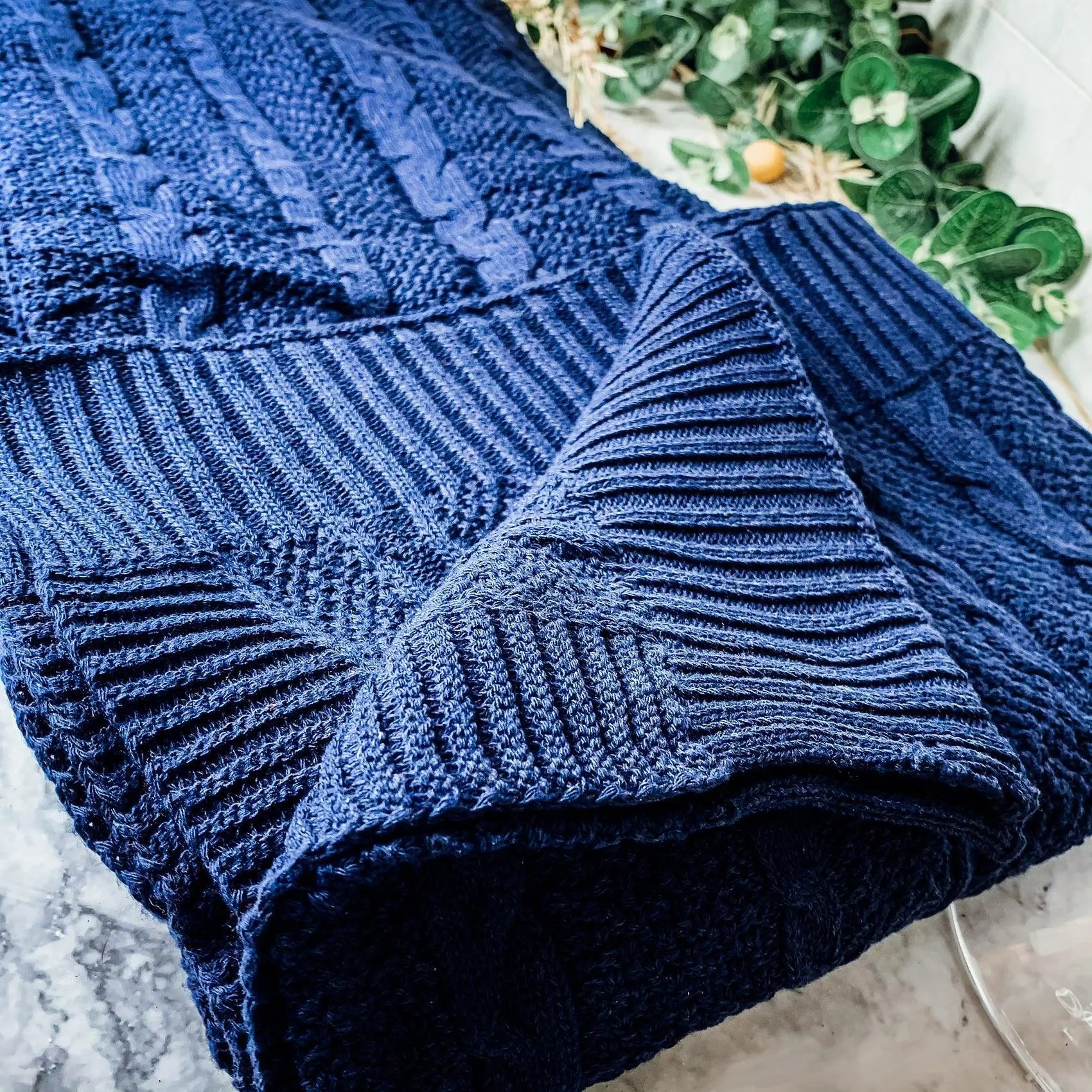 Cozy navy blue knitted blanket with cable and ribbed patterns, perfect for farmhouse decor
