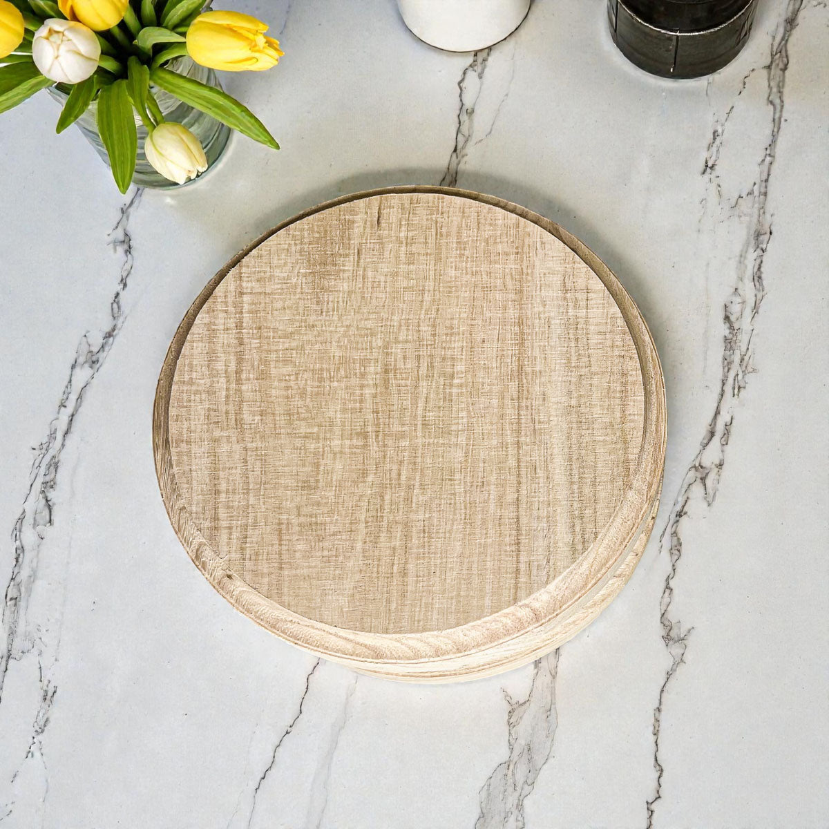 Round woven placemat on a marble surface with flowers in the background
