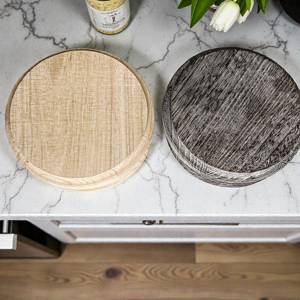 Two round woven coasters, one beige and one gray, on a marble countertop.