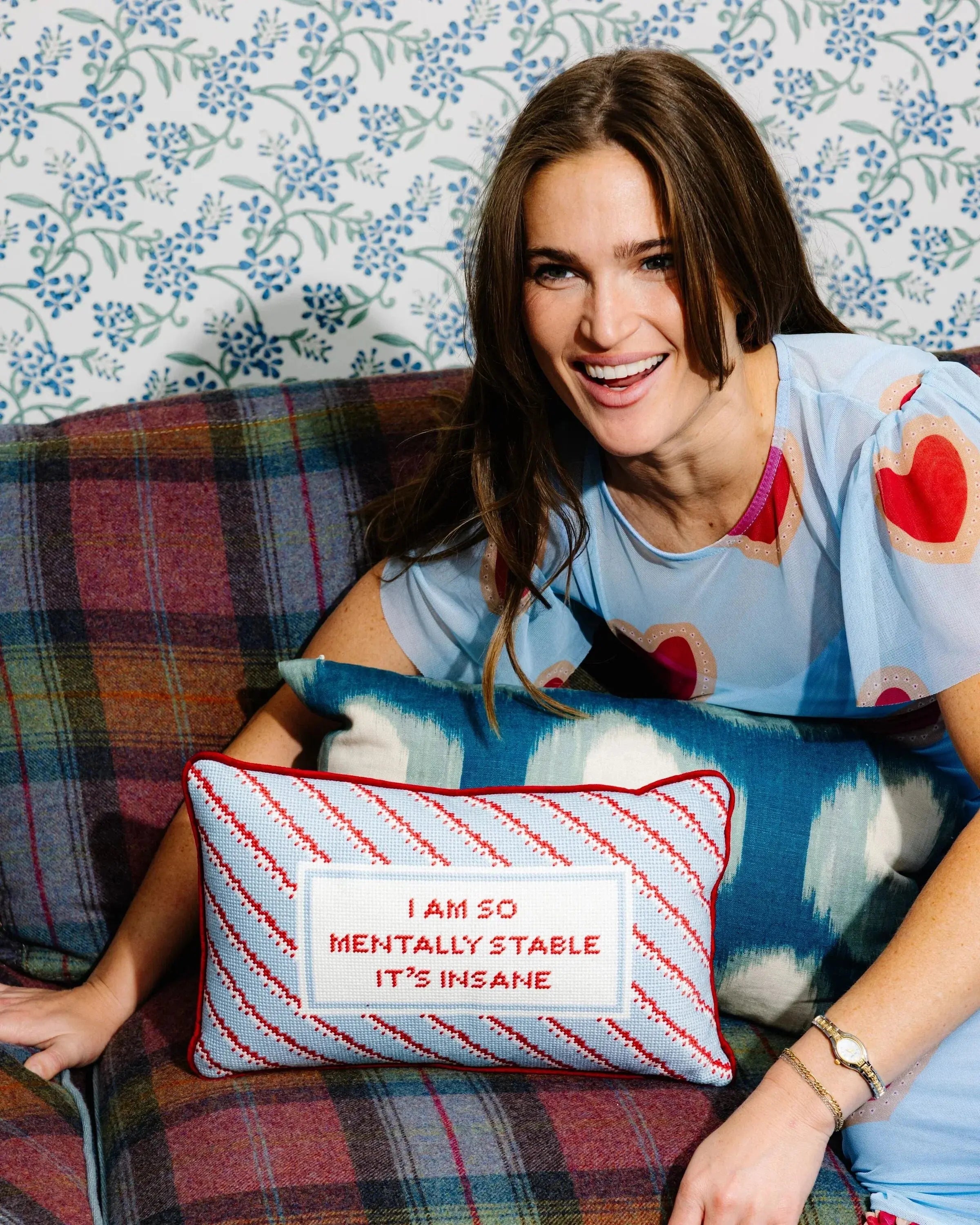 woman on a plaid couch with a Decorative pillow with text