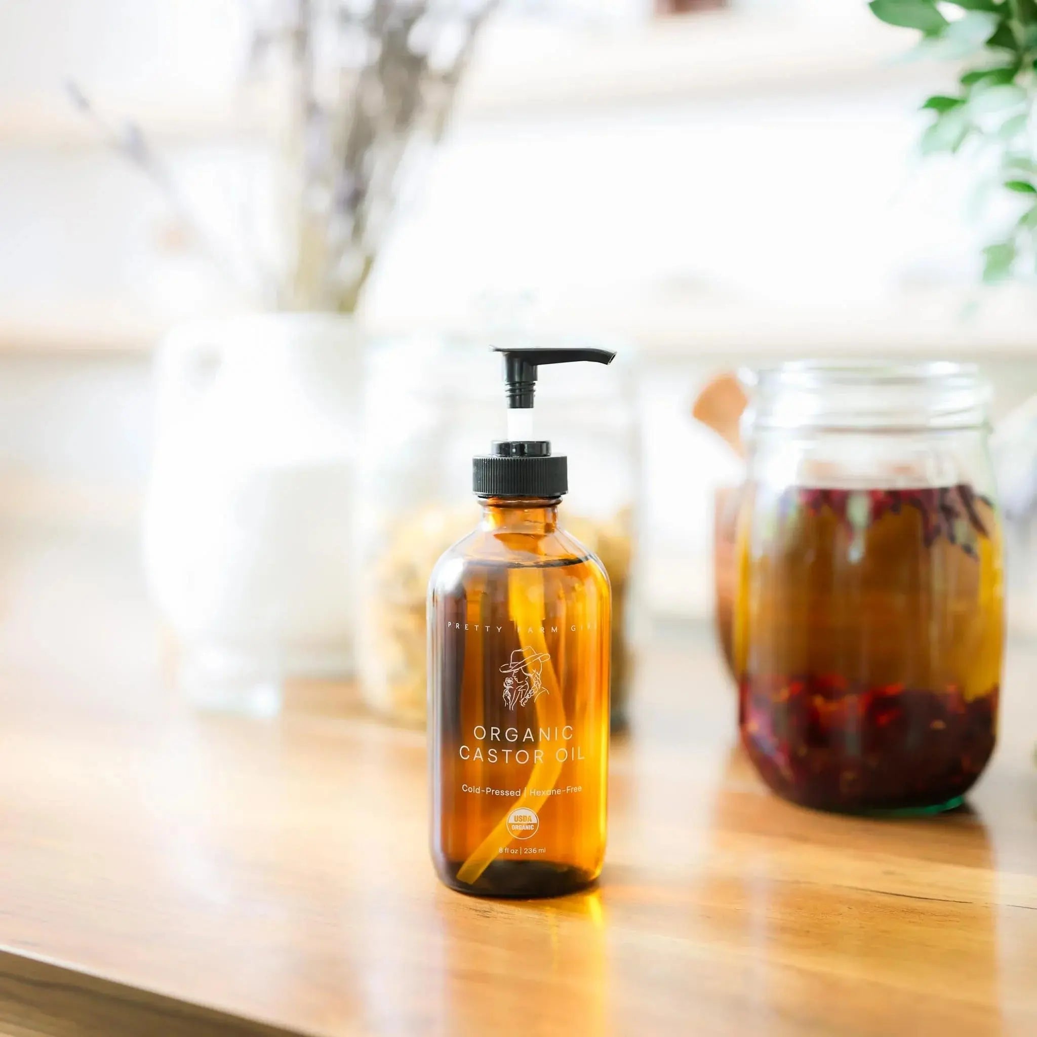 Organic castor oil in amber glass bottle with pump, farmhouse-style bath essential on wooden counter