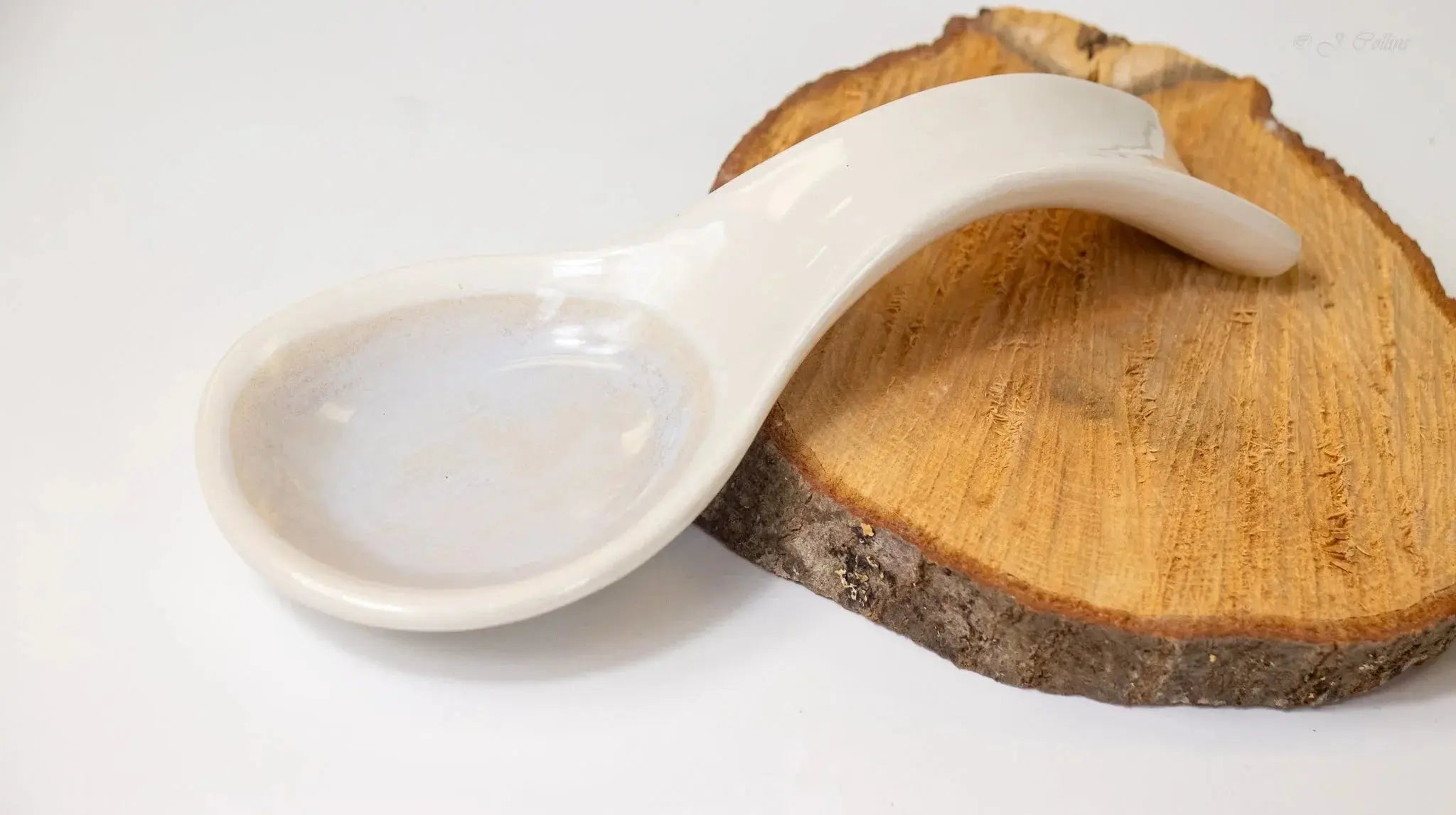 White ceramic spoon rest on rustic wood slice, farmhouse kitchen decor