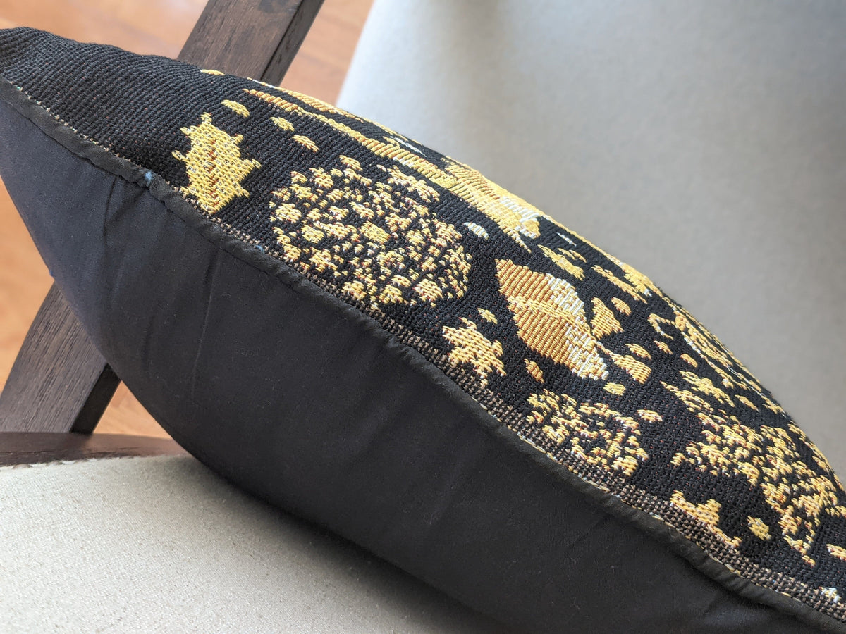 Decorative pillow with black and gold pattern on a chair